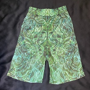 May include: Green and blue patterned shorts with an abstract design. The shorts have an elastic waistband and a knee-length cut. The pattern features swirling lines and geometric shapes, creating a unique and eye-catching look.