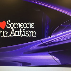 May include: A purple car with a white sticker that says "I love someone with autism" with a red heart.