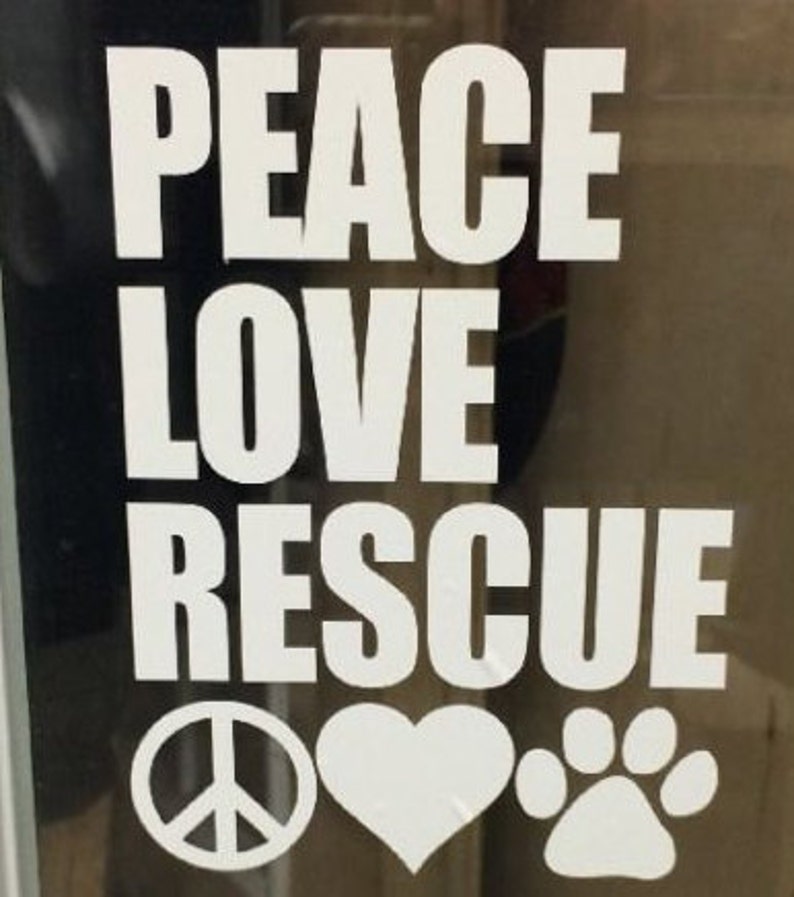 May include: White text on a dark background reads "PEACE LOVE RESCUE" with a peace symbol, heart, and paw print below. The image is likely a decal or sticker, promoting animal rescue and a message of peace and love.