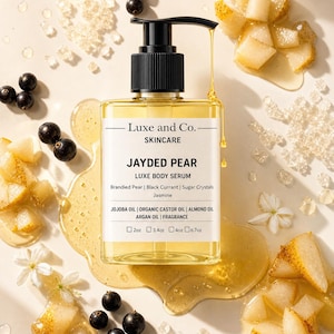May include: A clear glass bottle of "JAYDED PEAR LUXE BODY SERUM" by Luxe and Co. is surrounded by pears, black currants, and sugar crystals. The bottle has a black pump and contains a yellow liquid. The ingredients include Jojoba Oil and Jasmine.