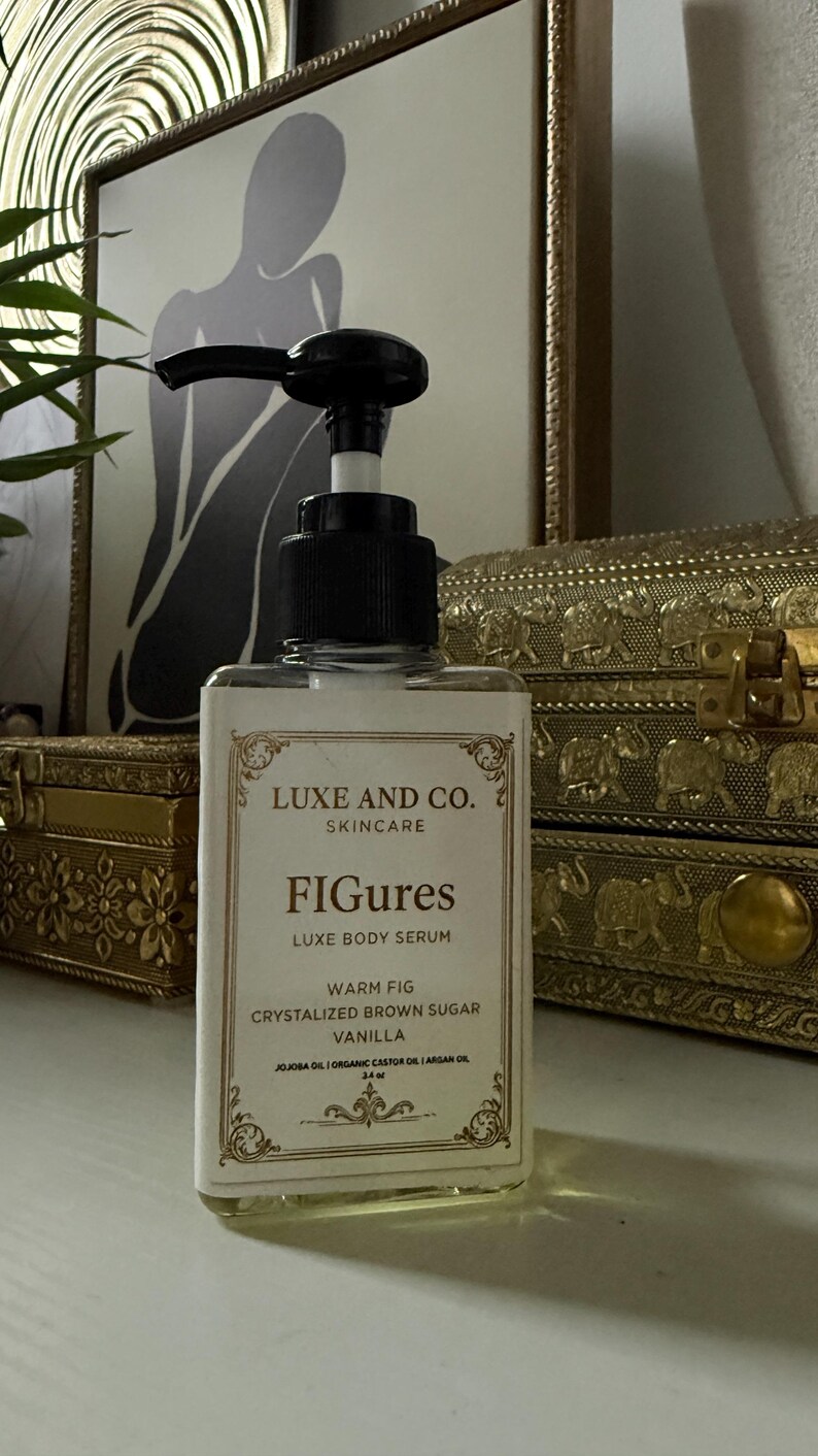 May include: A clear glass bottle of Luxe and Co. skincare serum with a black pump. The label reads "FIGures Luxe Body Serum" with "Warm Fig, Crystalized Brown Sugar, Vanilla" ingredients. The bottle is displayed in front of a decorative background.