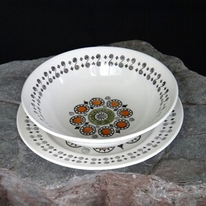 May include: A white ceramic bowl with a black and green geometric pattern. The bowl is sitting on a matching plate.