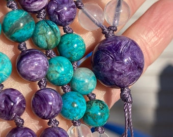 May include: A multi-strand beaded necklace with purple, blue, and clear beads. The necklace is made of various stones, including amethyst, turquoise, and clear quartz.