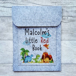 May include: Gray felt book cover with a personalized inscription that reads "Malcolm's Little Red Book". The cover features a colorful illustration of dinosaurs and a volcano.
