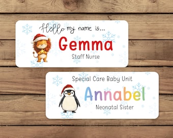 Peut inclure: Deux étiquettes nominatives aux coins arrondis. L'étiquette supérieure indique "Hello my name is... Gemma, Staff Nurse" avec un lion portant un chapeau de Père Noël. L'étiquette inférieure indique "Special Care Baby Unit Annabel, Neonatal Sister" avec un pingouin portant un chapeau de Père Noël.