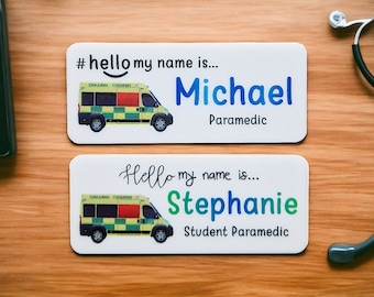 May include: Two white name tags with a green and yellow ambulance graphic. The top tag says "#hello my name is... Michael Paramedic". The bottom tag says "Hello my name is... Stephanie Student Paramedic".