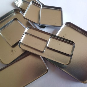 Op de afbeelding: Een set zilveren metalen bakjes in verschillende maten en vormen. De bakjes hebben gladde, reflecterende oppervlakken en zijn ideaal voor het organiseren van kleine items.