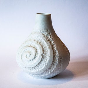 Könnte beinhalten: Weiße Keramikvase mit einem erhabenen Spiralmuster.