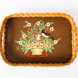 Puede incluir: Una bandeja de mimbre marrón con un diseño floral pintado. El diseño presenta un pájaro, flores y una cesta.