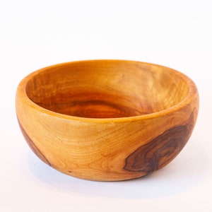 Könnte beinhalten: Eine kleine, runde Holzschale mit natürlicher Holzoptik. Die Schale hat eine glatte, polierte Oberfläche und ist aus hellem braunem Holz gefertigt.