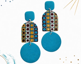 May include: A pair of dangle earrings featuring a square turquoise stud, a central arch-shaped piece with a grid pattern of blue, yellow, and dark red squares, and a large circular turquoise drop. The components are connected by silver-toned metal rings.