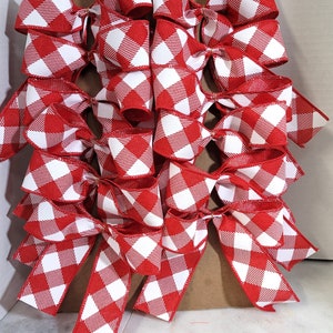 May include: A collection of red and white checkered bows. The bows are arranged in a layered pattern, showcasing the vibrant color and pattern. The bows are made of a ribbon material, perfect for crafting or gift wrapping.