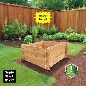 May include: A wooden raised garden bed, triple stacked, measuring 3 feet by 3 feet. The bed is made of light-colored wood and is set on a bed of brown mulch, surrounded by green grass and a wooden fence. The text "Extra Deep!" is in a yellow starburst.