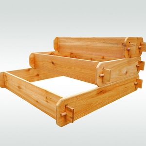 May include: A three-tiered wooden planter box made of natural cedar wood. The planter is assembled with interlocking pieces and features a natural wood finish.