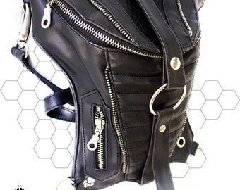Könnte beinhalten: Schwarze Hüfttasche aus Leder mit mehreren Reißverschlussfächern und silberfarbenen Beschlägen. Die Tasche hat ein strukturiertes Panel und einen Riemen mit Metallring. Das Design beinhaltet ein Pfotenabdruck-Logo.