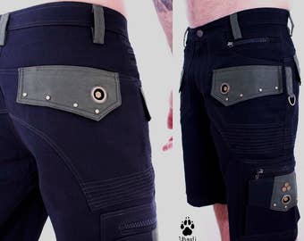 Könnte beinhalten: Schwarze Cargo-Shorts mit einem grünen Stoff-Patch auf jeder Seite. Die Patches haben einen runden Metallakzent und mehrere silberne Nieten. Die Shorts haben mehrere Nähte und Taschen.