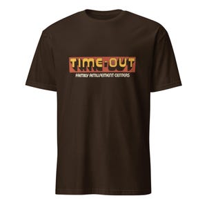 May include: A brown t-shirt featuring the text "TIME-OUT" in a retro font, with "FAMILY AMUSEMENT CENTERS" below. The design is in orange and yellow, set against the dark brown fabric. A casual, short-sleeved tee.