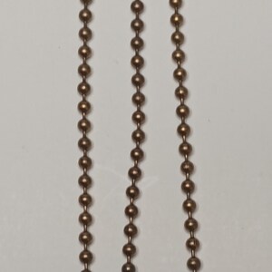 May include: Three gold-toned ball chains with a bell at the end of each chain.