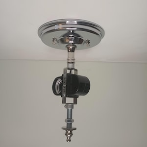 May include: A chrome ceiling fixture with a black electrical socket and a metal rod extending down from the socket.