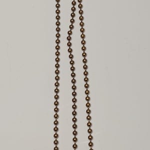 May include: Three gold chains with a ball at the end of each chain.