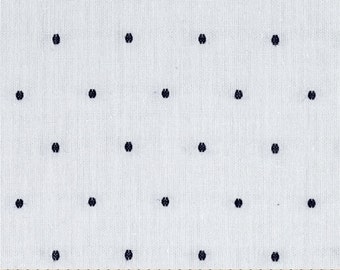 May include: White fabric with a repeating pattern of small, dark blue, oval-shaped designs. The fabric is measured with a wooden ruler, showing increments in inches.