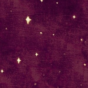 Pode incluir: Um tecido bordô escuro com uma aparência texturizada, apresentando acentos dispersos em forma de estrela brilhante em um tom dourado. As estrelas variam em tamanho e brilho, criando um padrão celestial na superfície.