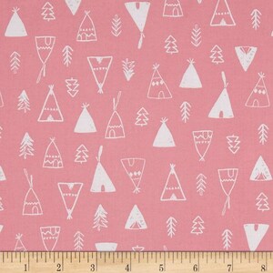 Puede incluir: Tela rosa con un patrón blanco repetido de tipis y árboles. La tela se mide con una regla en pulgadas.