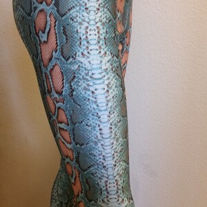 May include: Teal and pink snakeskin print leggings. The leggings are fitted and have a high waist.