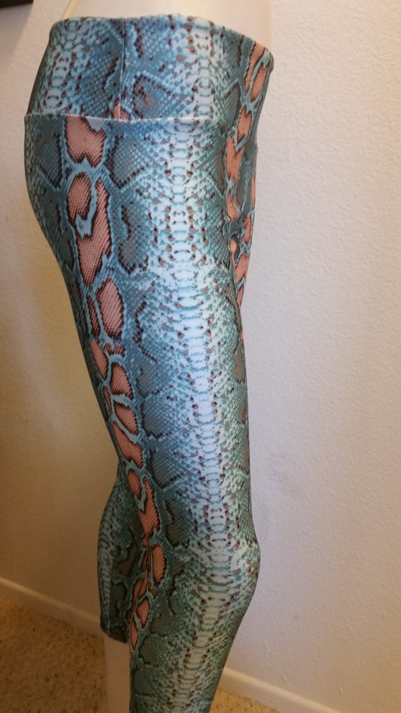 May include: Teal and pink snakeskin print leggings. The leggings are fitted and have a high waist.