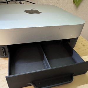 May include: A silver desktop computer with a black drawer that slides out. The drawer has two compartments.
