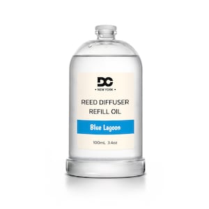 May include: A clear glass bottle containing reed diffuser refill oil. The label features the text DC NEW YORK, REED DIFFUSER REFILL OIL, Blue Lagoon, and 100mL 3.4oz. The bottle has a screw-top cap and is filled with a transparent liquid.
