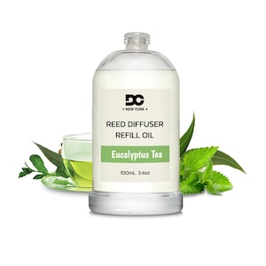 May include: Clear glass bottle of Eucalyptus Tea Reed Diffuser Refill Oil, 100ml/3.4oz, with a black label and the DC New York logo. The bottle is surrounded by green leaves.