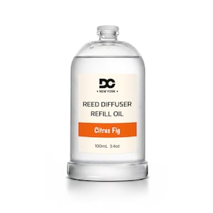 May include: A clear glass bottle containing reed diffuser refill oil. The label features the text DC NEW YORK, REED DIFFUSER REFILL OIL, Citrus Fig, and 100mL 3.4oz. The bottle has a rounded shoulder, a narrow neck, and a small clear cap on top.