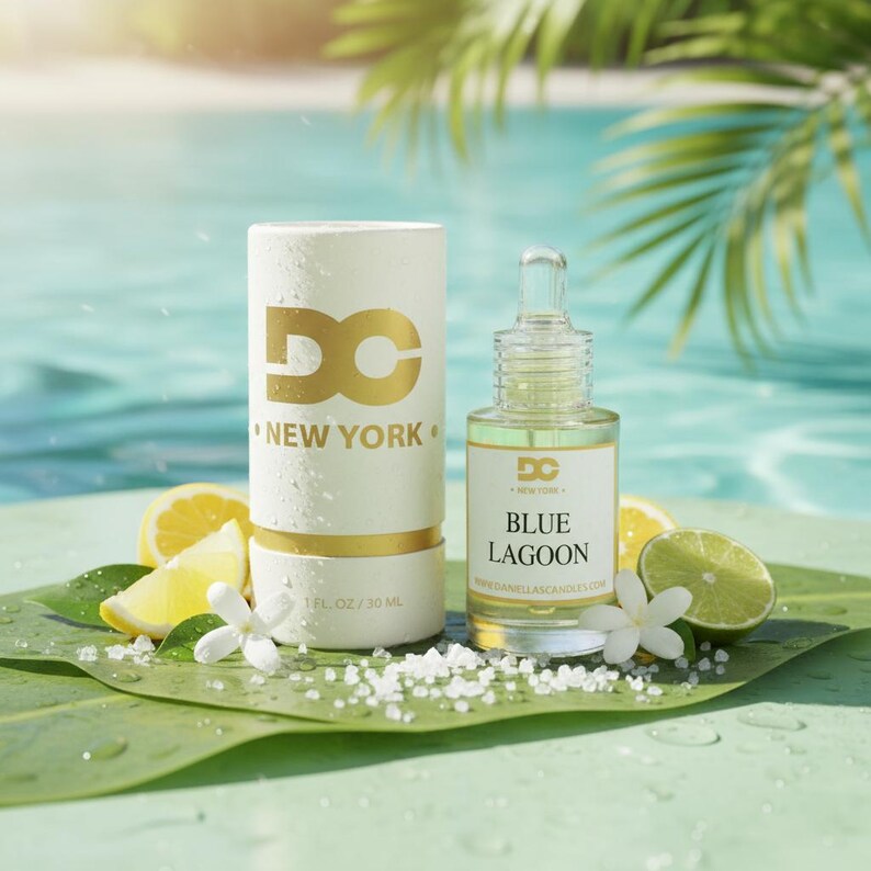 Puede incluir: Un recipiente cil&iacute;ndrico blanco y una botella de vidrio de aceite "Blue Lagoon" se muestran con rodajas de lim&oacute;n y flores blancas. El recipiente tiene letras doradas que dicen "DC NEW YORK". La botella tiene un cuentagotas y una etiqueta dorada.