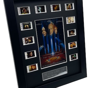 May include: A black framed movie prop display featuring film strips from the movie "The Fifth Element" (1997). The display includes a poster of the movie with Bruce Willis, Gary Oldman, and Milla Jovovich. The text "The Fifth Element (1997)" and "Mini Montage: 14/500" is printed on the display.