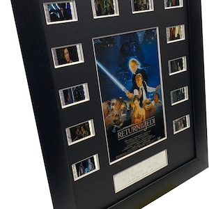 Puede incluir: Un póster de película enmarcado en negro con una escena de Star Wars: El Retorno del Jedi. El póster está rodeado por 10 tiras de celdas de película. El texto en el póster dice "Star Wars: El Retorno del Jedi". El texto en la placa debajo del póster dice "Return of the Jedi 1983 41st Vintage 385/500".