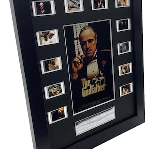 Puede incluir: Un p&oacute;ster de pel&iacute;cula enmarcado en negro con un borde plateado. El p&oacute;ster presenta un primer plano de Marlon Brando como Don Vito Corleone de la pel&iacute;cula "El Padrino". El p&oacute;ster tambi&eacute;n incluye una tarjeta de t&iacute;tulo que dice "El Padrino" y una tarjeta de texto m&aacute;s peque&ntilde;a que dice "The Godfather 1972/Paramount - Montage - 1x1500". El marco incluye nueve im&aacute;genes de celdas de pel&iacute;cula m&aacute;s peque&ntilde;as de la pel&iacute;cula.