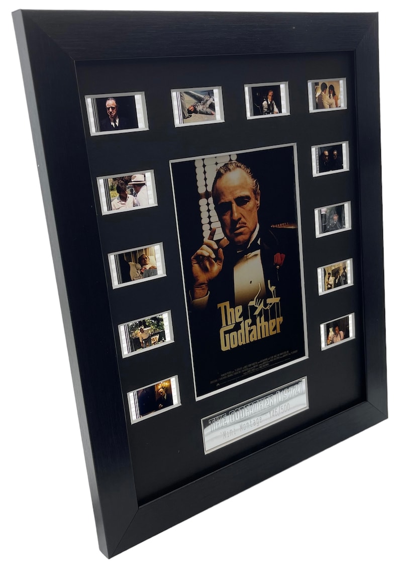 Puede incluir: Un p&oacute;ster de pel&iacute;cula enmarcado en negro con un borde plateado. El p&oacute;ster presenta un primer plano de Marlon Brando como Don Vito Corleone de la pel&iacute;cula "El Padrino". El p&oacute;ster tambi&eacute;n incluye una tarjeta de t&iacute;tulo que dice "El Padrino" y una tarjeta de texto m&aacute;s peque&ntilde;a que dice "The Godfather 1972/Paramount - Montage - 1x1500". El marco incluye nueve im&aacute;genes de celdas de pel&iacute;cula m&aacute;s peque&ntilde;as de la pel&iacute;cula.