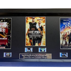 Peut inclure: Un ensemble de trois affiches de films encadrées : "Shaun of the Dead", "Hot Fuzz" et "Le Monde de la Fin". Chaque affiche est entourée d'un passe-partout noir et comprend une petite photo de film encadrée en dessous. L'ensemble est encadré dans un cadre en bois noir.