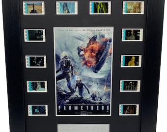 May include: A black framed movie prop display featuring film cells from the movie Prometheus. The display includes a poster of the movie with the title "Prometheus" and the text "From the director of Alien and Gladiator". The display also includes a silver plaque with the text "Prometheus (2012) Kins Montage 124/300".