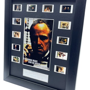 May include: A framed movie poster featuring a close-up of Marlon Brando as Don Vito Corleone from the film "The Godfather". The poster includes a quote from the film: "I'm gonna make him an offer he can't refuse."
