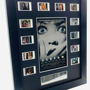 Könnte beinhalten: Ein gerahmtes Filmplakat für den Film "Scream" (1996) mit einer Nahaufnahme des Gesichts der Hauptfigur. Das Plakat ist von 9 Filmstreifen aus dem Film umgeben. Das Plakat ist in Schwarz gerahmt und hat eine silberne Plakette mit dem Titel des Films und der Nummer 251/500.