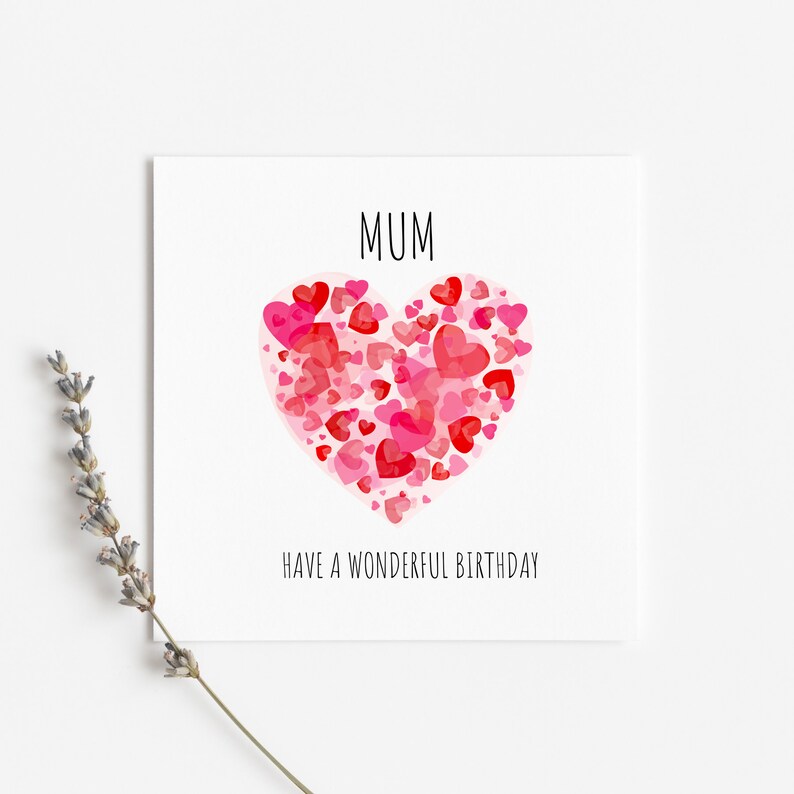 May include: A white card with the word "MUM" in black text. A large pink heart made of smaller pink and red hearts is in the center of the card. The text "HAVE A WONDERFUL BIRTHDAY" is below the heart.