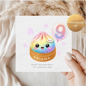 May include: A square greeting card featuring a rainbow-coloured, glittery dumpling character in a wooden steamer basket with the name ARIANA printed on it. A balloon with the number 9, small stars, and the text HAPPY 9TH BIRTHDAY TO A SPECIAL GIRL.