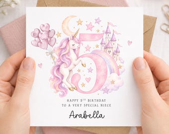 May include: A square birthday greeting card featuring a large pink number 5, a white unicorn with a pink and purple mane, a castle, a rainbow, a crescent moon, stars, and a bunch of heart-shaped balloons. Text reads: HAPPY 5TH BIRTHDAY TO A VERY SPECIAL NIECE Arabella.