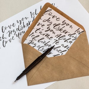 May include: A brown envelope with a white card inside. The card has a handwritten message in black ink that says "I love you Ich love you Icl ove you'd Jeg elsker dig dich Jeg elsker ve I love you ve you Aloha t'aime Te an Ich lieberlich Jeg els d".