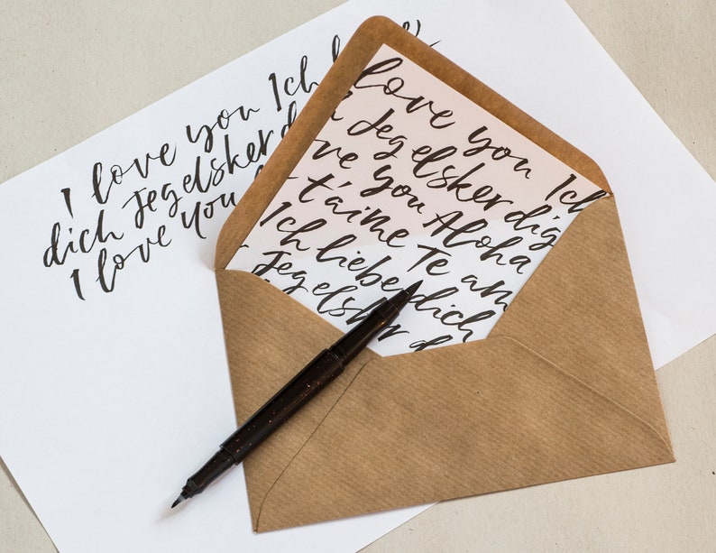 May include: A brown envelope with a white card inside. The card has a handwritten message in black ink that says "I love you Ich love you Icl ove you'd Jeg elsker dig dich Jeg elsker ve I love you ve you Aloha t'aime Te an Ich lieberlich Jeg els d".