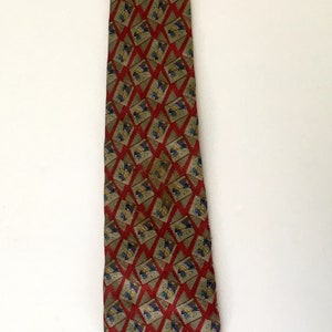 May include: A patterned necktie with a repeating geometric design. The tie features a red diamond pattern with a tan background and accents of blue and yellow. The tie is displayed against a white background.