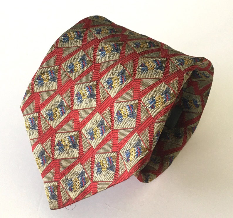 May include: A patterned tie featuring a repeating design of diamond shapes with a red grid overlay. The diamonds have a beige background with blue, yellow, and red accents. The tie is made of a shiny fabric.