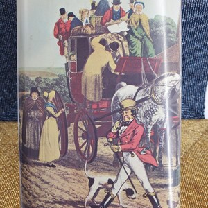 May include: A rectangular tin with a red border displays a vintage illustration of a horse-drawn carriage with passengers and people in period clothing. A man in a red coat walks with a dog.